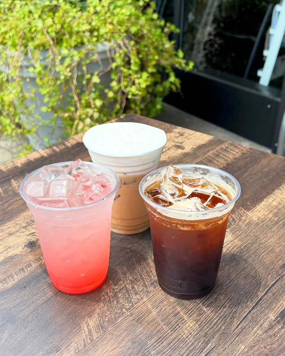 Three iced drinks on the wooden table outside, next to the ivy planter