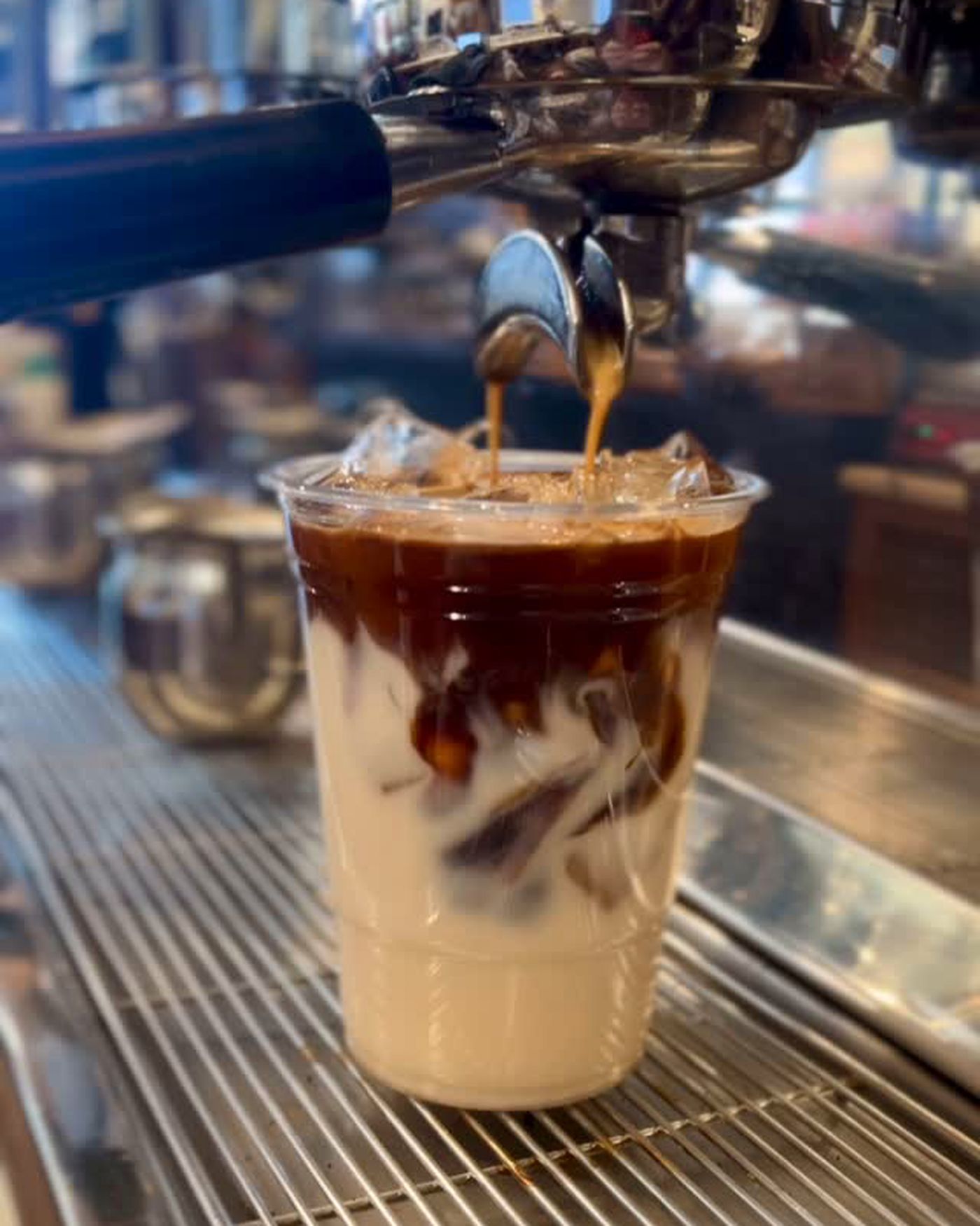 Espresso pulling from the machine into a cup of milk over ice