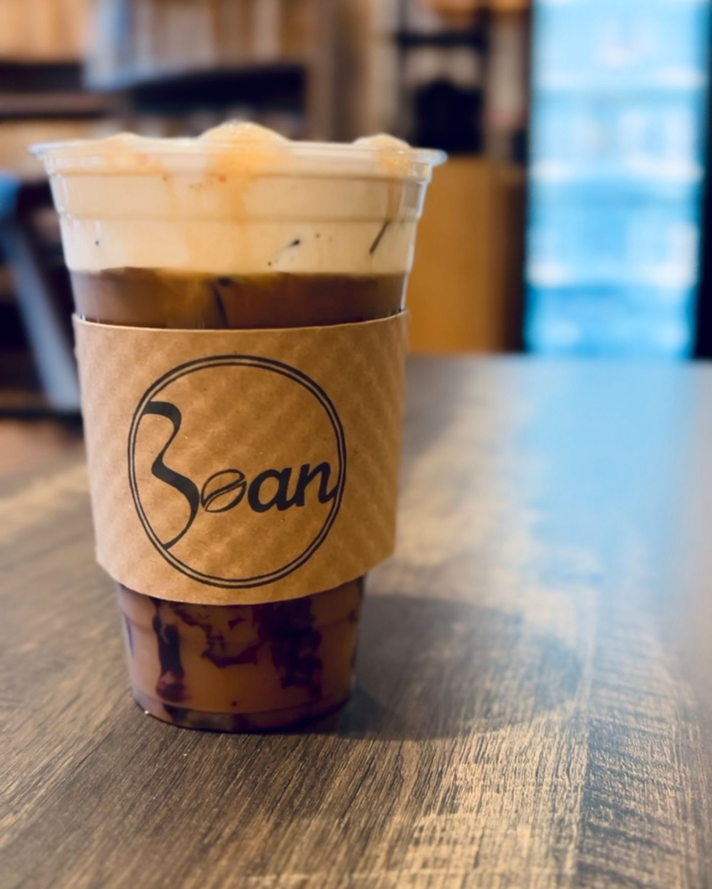 An iced drink in a kraft Bean sleeve on the counter